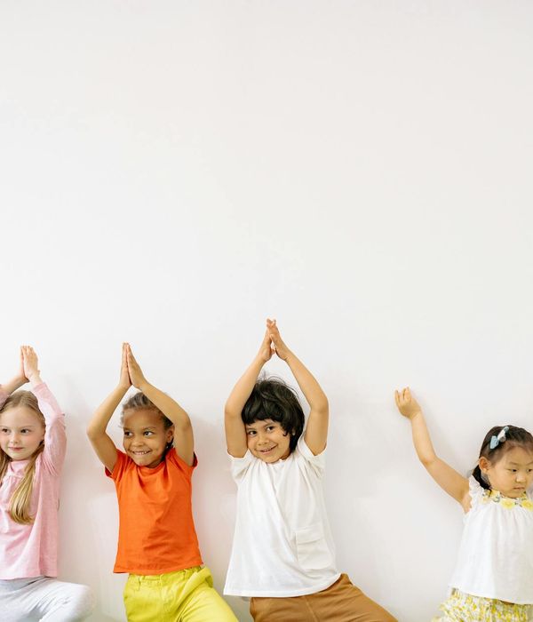 Happy child doing a simple yoga pose in a bright room.